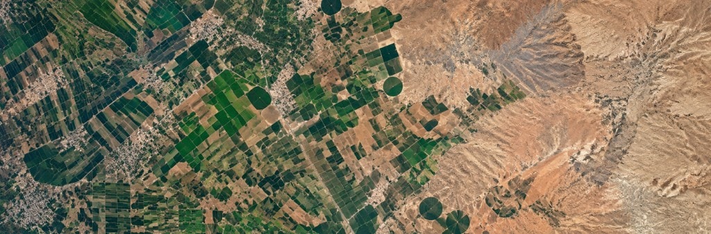 Satellite view of irrigated crop circles giving way to arid badlands